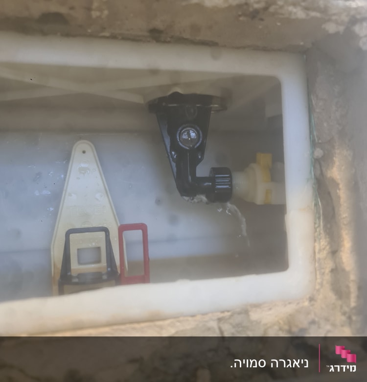 שסתום מים שחור בתוך מיכל פלסטיק לבן
